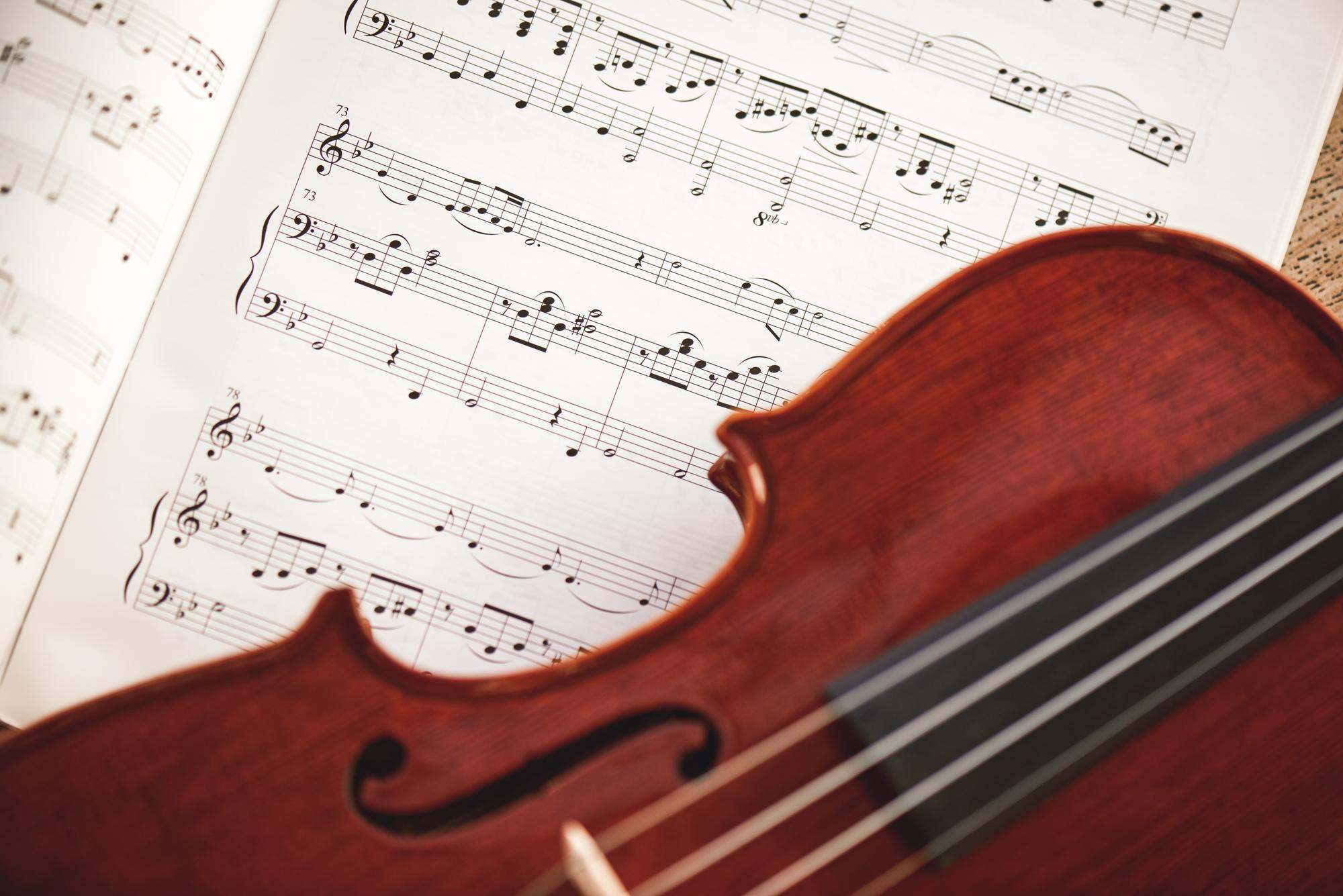 in love with classic music close up view of brown violin lying on music score