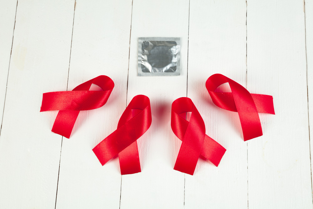 aids awareness sign red ribbons on white wooden table background with condom world aids day concept the health help care support hope illness healthcare concept